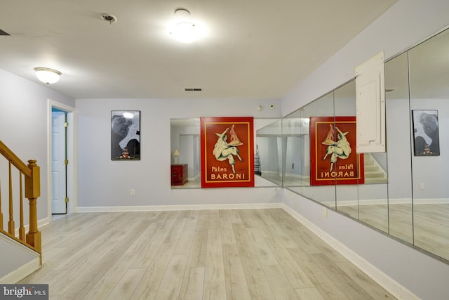 hallway featuring visible vents, wood finished floors, baseboards, and stairs