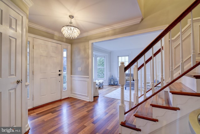 entryway with wainscoting, a chandelier, a decorative wall, stairway, and hardwood / wood-style floors