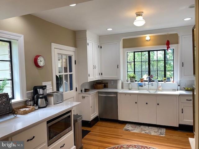 kitchen featuring appliances with stainless steel finishes, white cabinets, healthy amount of natural light, light countertops, and recessed lighting