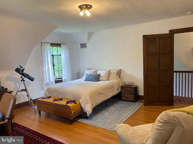 bedroom featuring wood finished floors, lofted ceiling, and baseboards