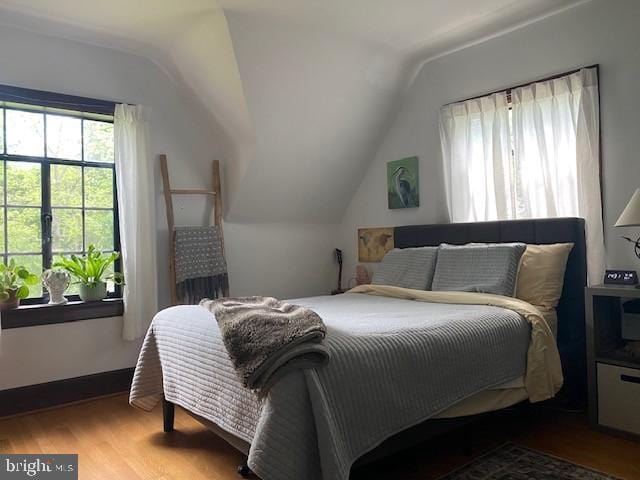 bedroom with lofted ceiling and wood finished floors