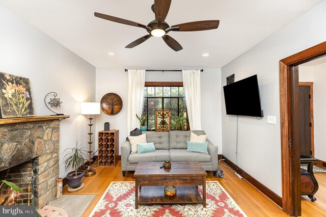 living area with a ceiling fan, wood finished floors, a fireplace, baseboards, and recessed lighting