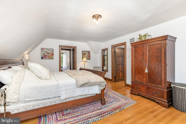 bedroom with light wood-style floors and vaulted ceiling