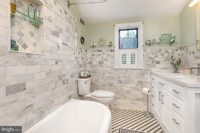 full bath featuring a bath, toilet, tile walls, vanity, and tile patterned floors