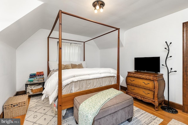 bedroom with lofted ceiling, wood finished floors, and baseboards