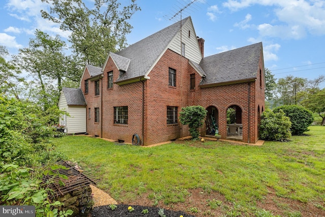 view of home's exterior with brick siding, a lawn, and roof with shingles