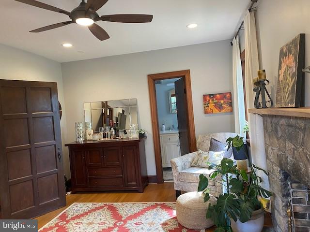 living area featuring light wood-style floors, a ceiling fan, a fireplace, and recessed lighting