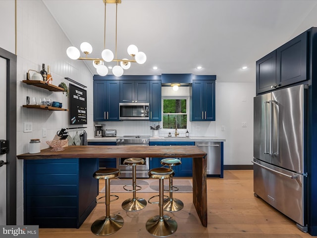 209 Hogan Dr, Basye, VA 22810 - kitchen with appliances with stainless steel finishes, wooden counters, blue cabinets, a breakfast bar area, and light wood-style flooring