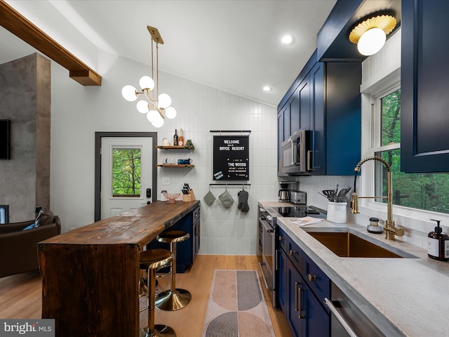 209 Hogan Dr, Basye, VA 22810 - kitchen featuring blue cabinetry, appliances with stainless steel finishes, a sink, vaulted ceiling, and light wood-type flooring