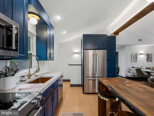 209 Hogan Dr, Basye, VA 22810 - kitchen featuring appliances with stainless steel finishes, blue cabinetry, lofted ceiling, a sink, and light wood-type flooring