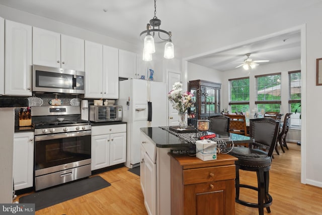 5533 Westcott Cir, Frederick, MD 21703 - kitchen featuring stainless steel appliances, light wood-style flooring, dark countertops, a kitchen island, and white cabinets