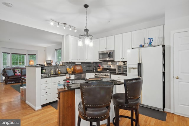 5533 Westcott Cir, Frederick, MD 21703 - kitchen featuring appliances with stainless steel finishes, dark countertops, white cabinetry, tasteful backsplash, and light wood-style flooring