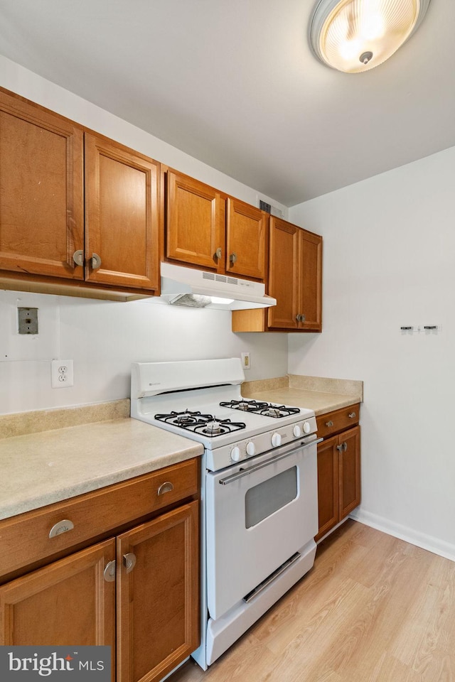 4931 Americana Dr Unit 4931B, Annandale, VA 22003 - kitchen with white gas range oven, under cabinet range hood, brown cabinetry, and light wood-style floors