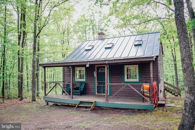 view of front of house with a standing seam roof, a chimney, and metal roof