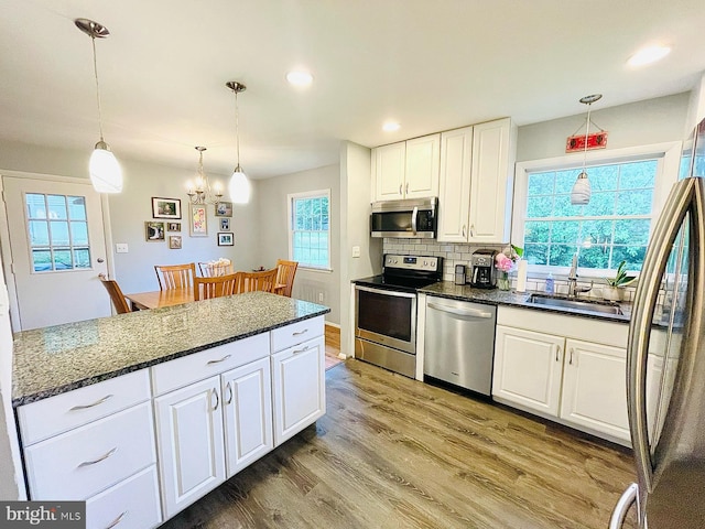 12112 Bayswater Rd, Gaithersburg, MD 20878 - kitchen featuring appliances with stainless steel finishes, a sink, white cabinetry, light wood-style flooring, and hanging light fixtures