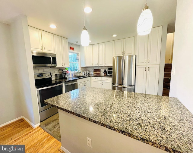 12112 Bayswater Rd, Gaithersburg, MD 20878 - kitchen featuring stainless steel appliances, a sink, light wood-style flooring, white cabinetry, and decorative backsplash