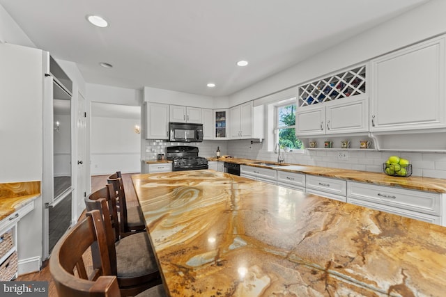 kitchen featuring black appliances, white cabinets, a sink, backsplash, and butcher block counters