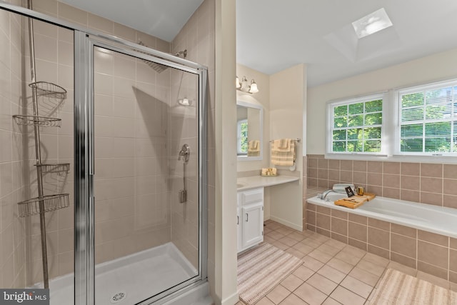 bathroom featuring tile patterned flooring, a shower stall, a bath, vanity, and a skylight