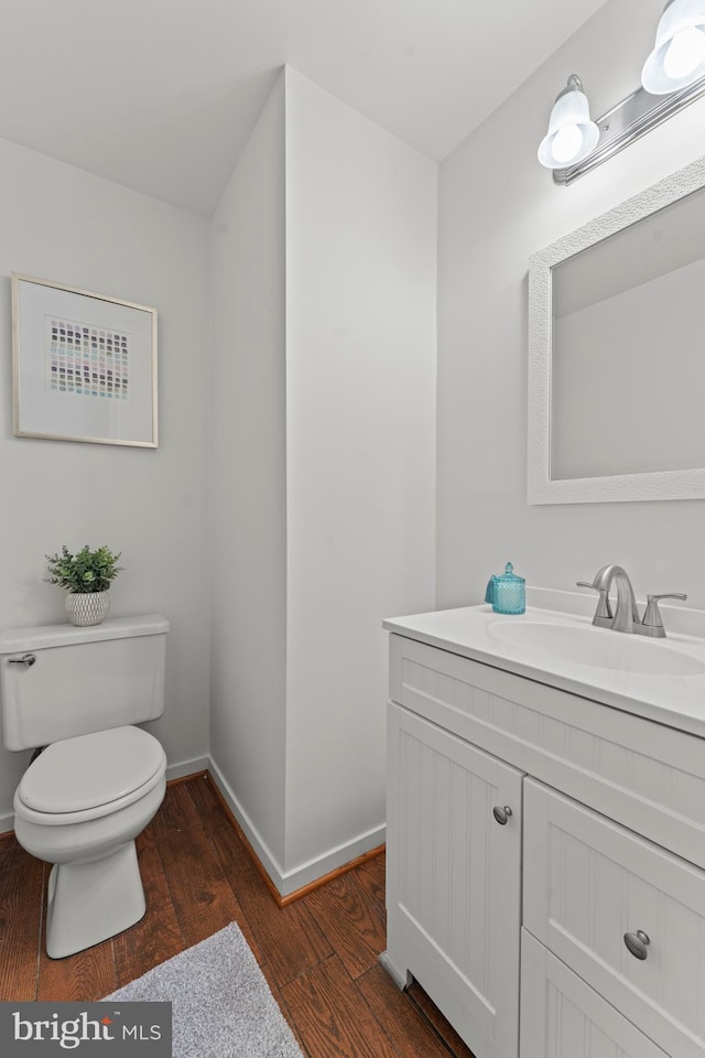 bathroom featuring wood finished floors, toilet, vanity, and baseboards