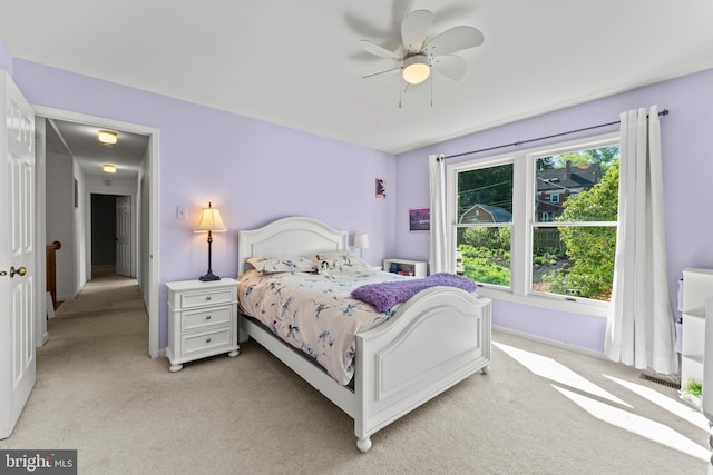 bedroom featuring light carpet, baseboards, and a ceiling fan