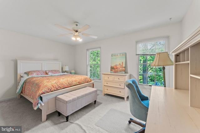 bedroom featuring light carpet, ceiling fan, a desk, and baseboards