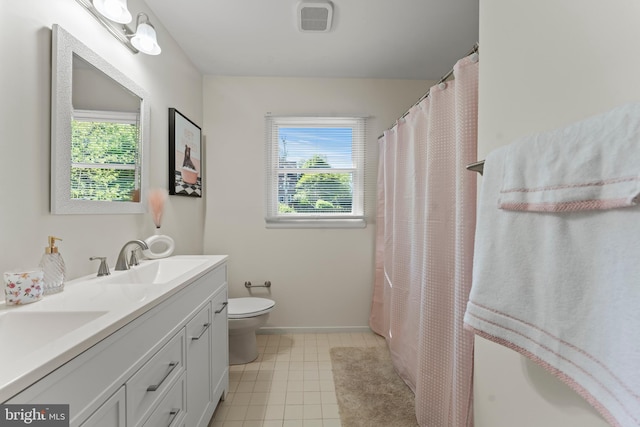 full bathroom featuring toilet, double vanity, tile patterned floors, and baseboards