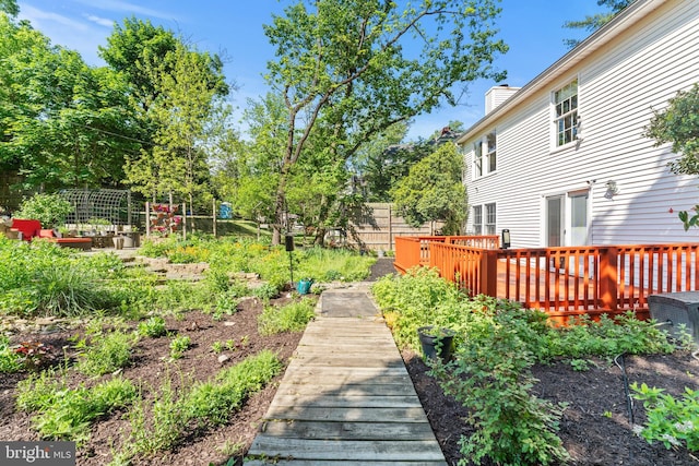 view of yard featuring a deck, fence, and a vegetable garden