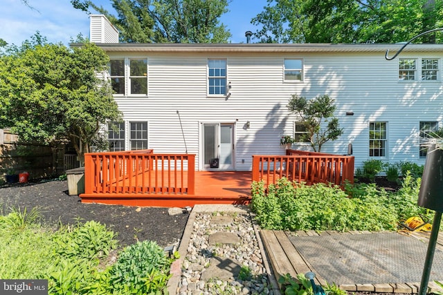 rear view of house featuring a deck, fence, and a chimney