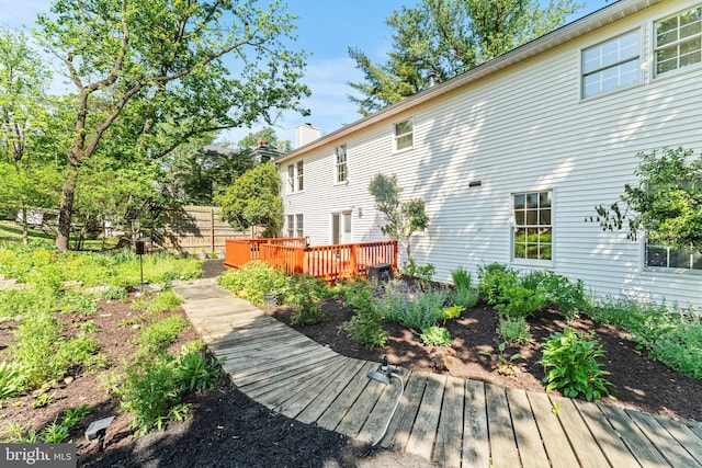 back of house featuring a wooden deck, a chimney, and fence
