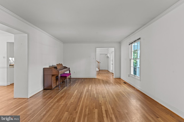 unfurnished room featuring light wood-style floors, crown molding, and baseboards