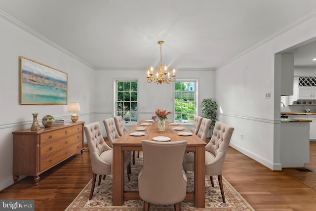 dining room with a chandelier, wood finished floors, ornamental molding, and baseboards
