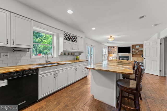 kitchen with dishwasher, wood counters, a sink, a fireplace, and healthy amount of natural light