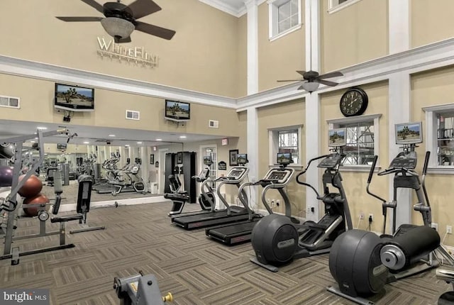 workout area featuring a ceiling fan, visible vents, and a towering ceiling