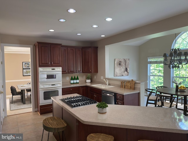 kitchen with a sink, a kitchen breakfast bar, a peninsula, light countertops, and appliances with stainless steel finishes