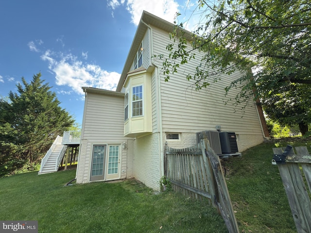 back of property with cooling unit, fence, a lawn, a deck, and stairs