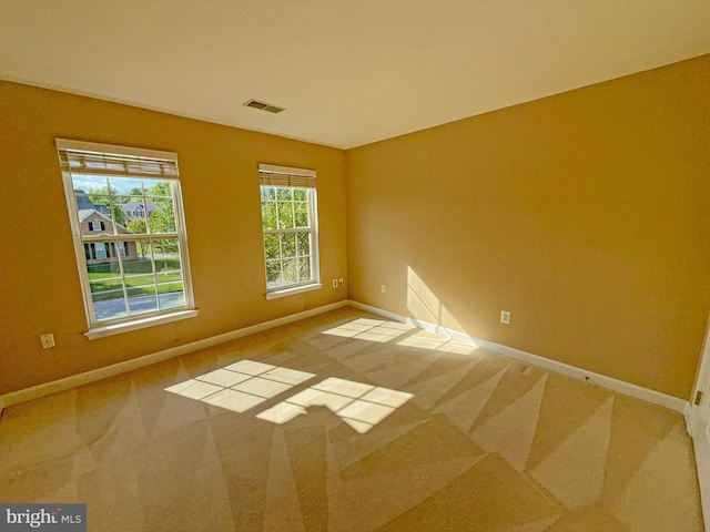 empty room with carpet, visible vents, and baseboards