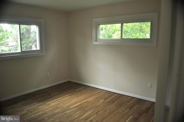 empty room featuring baseboards and dark wood-style floors