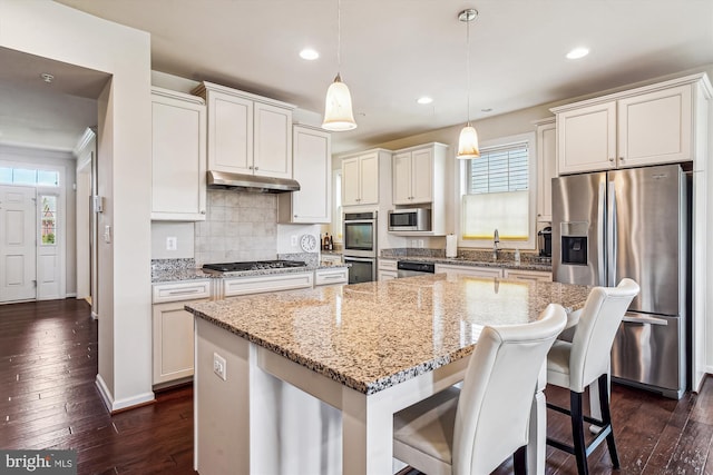 10809 Glowing Hearth Way, Monrovia, MD 21770 - kitchen featuring stainless steel appliances, under cabinet range hood, a center island, dark wood-style flooring, and light stone counters