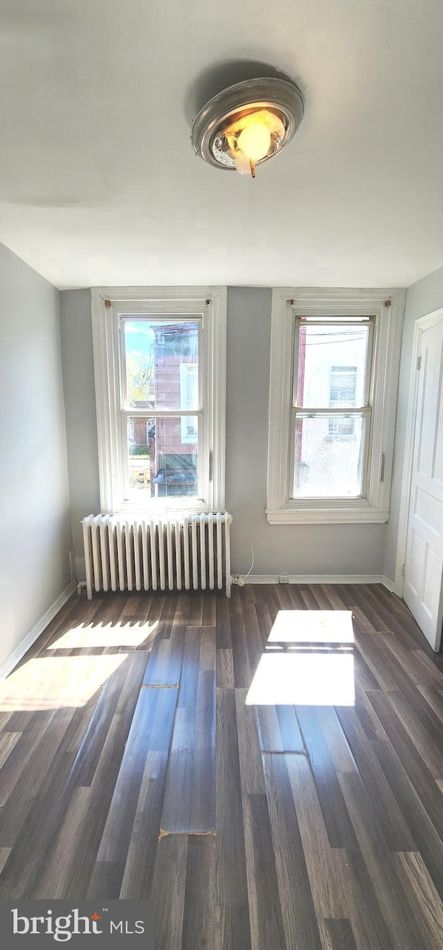 unfurnished room featuring radiator heating unit, baseboards, and plenty of natural light