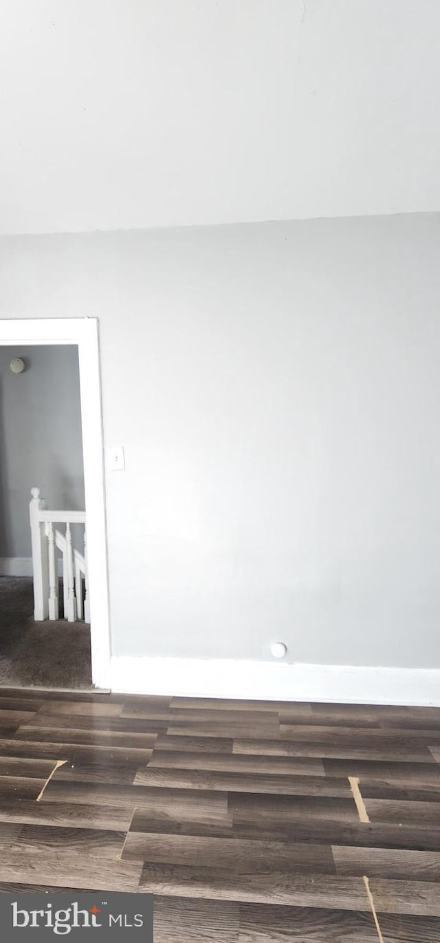 spare room with baseboards and dark wood-style floors