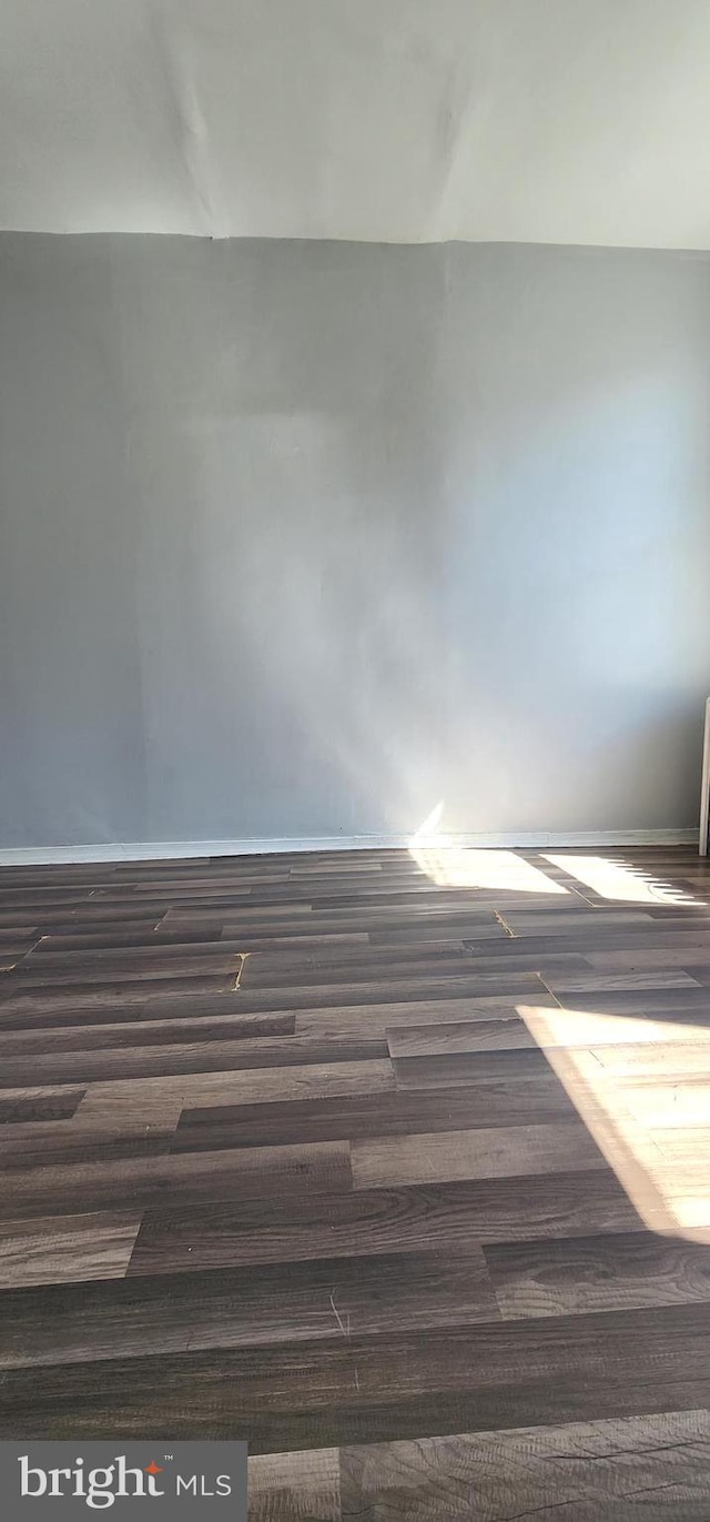 unfurnished room with dark wood finished floors and baseboards