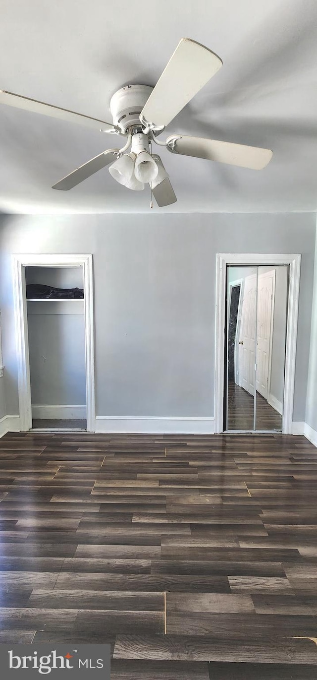 unfurnished bedroom with dark wood-style floors, baseboards, and a ceiling fan