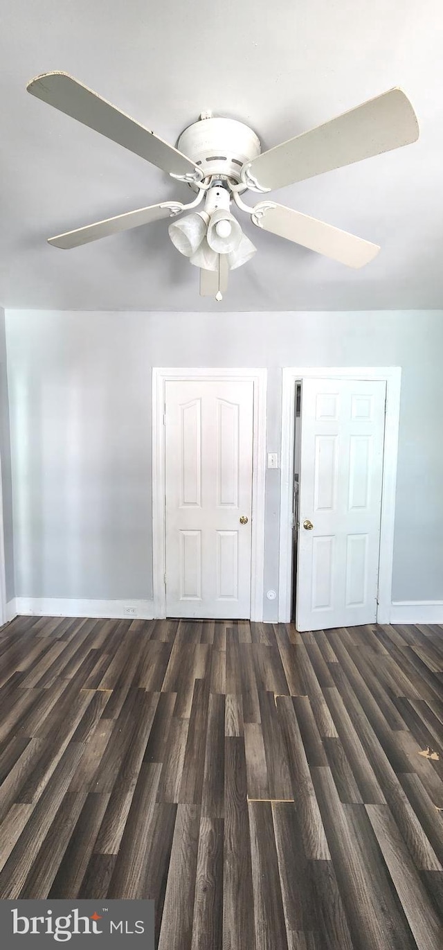 spare room featuring a ceiling fan, dark wood-style floors, and baseboards