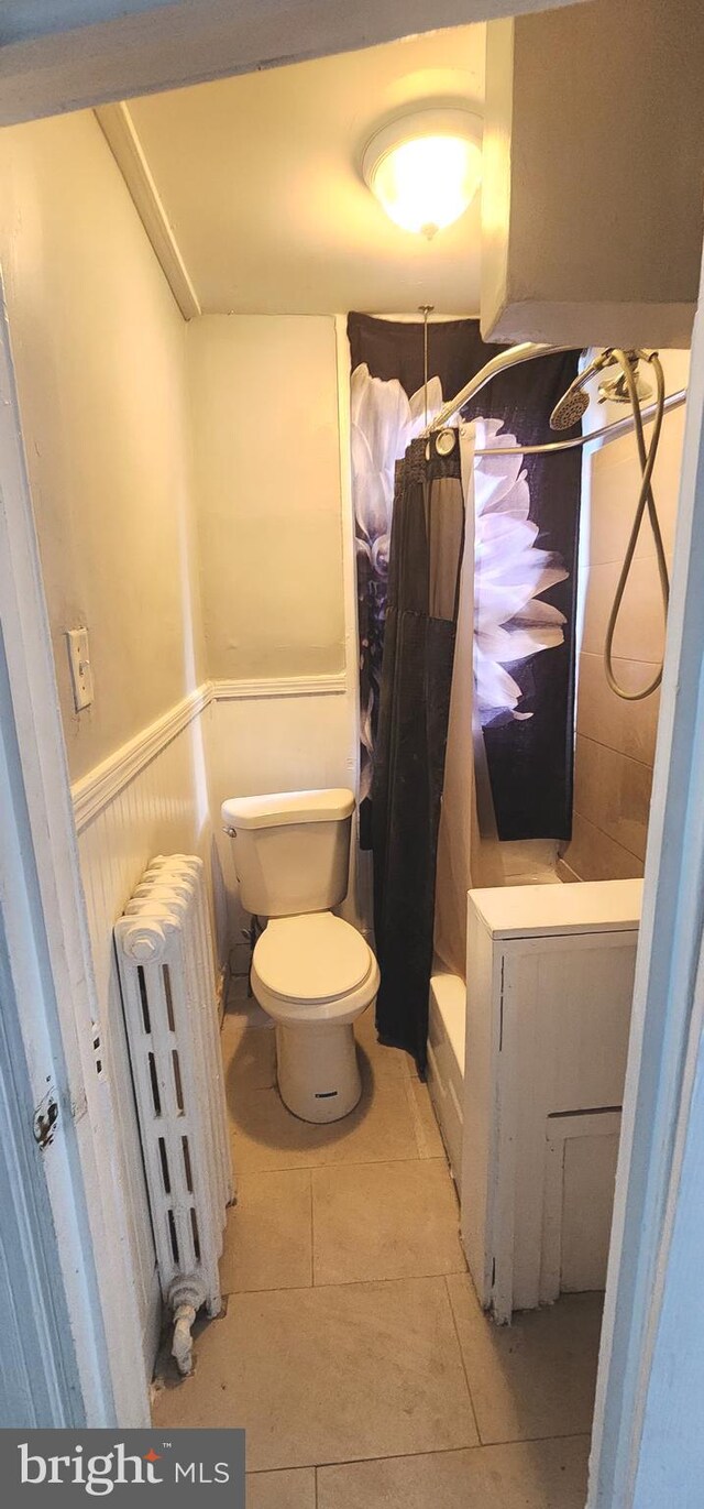 bathroom featuring radiator heating unit, wainscoting, toilet, and tile patterned flooring