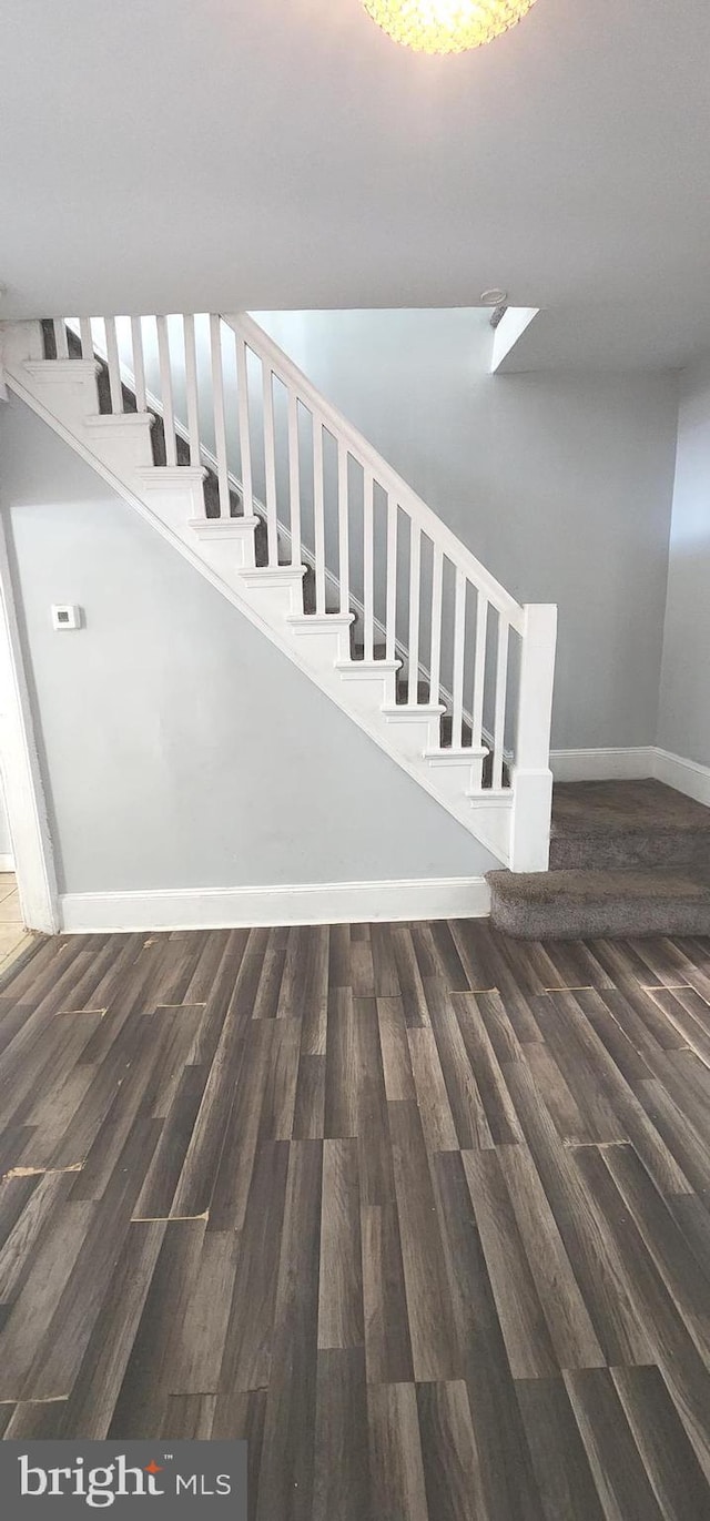 staircase featuring baseboards and wood finished floors