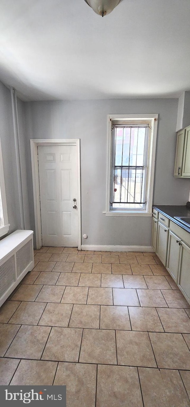 foyer entrance with light tile patterned flooring, radiator heating unit, and baseboards