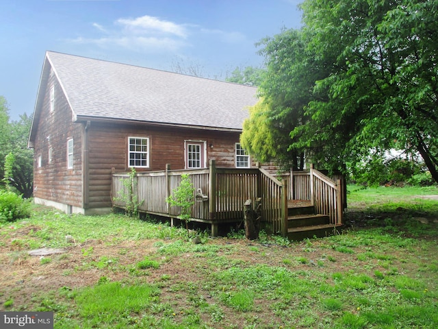 rear view of property with a wooden deck and a shingled roof