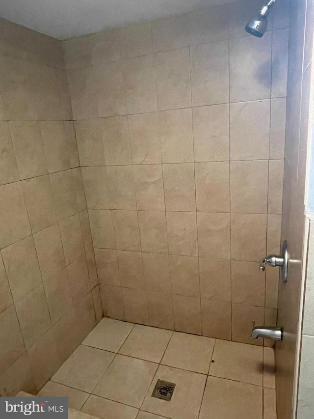 full bath featuring tiled shower and tile patterned flooring