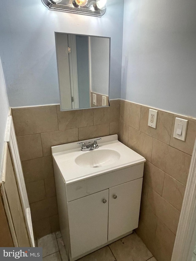 bathroom featuring tile walls, tile patterned flooring, vanity, and wainscoting