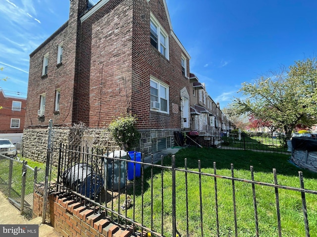 view of home's exterior featuring cooling unit, brick siding, fence, and a lawn
